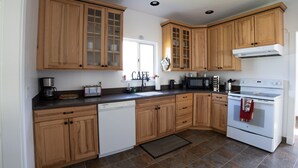 A kitchen with wooden cabinets, a dishwasher, a microwave, a stove, and a sink.