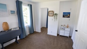 A room with a desk, a chair, a lamp, a small plant, and a door leading to another room.