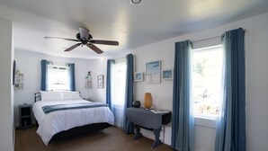 A bedroom with a bed, a bedside table, a floor lamp, a ceiling fan, and a window with curtains.