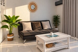 A modern living room with a sofa, a coffee table, and potted plants.