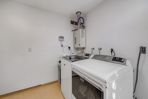 A laundry room with a front-loading washing machine, a dryer, and a steam iron.