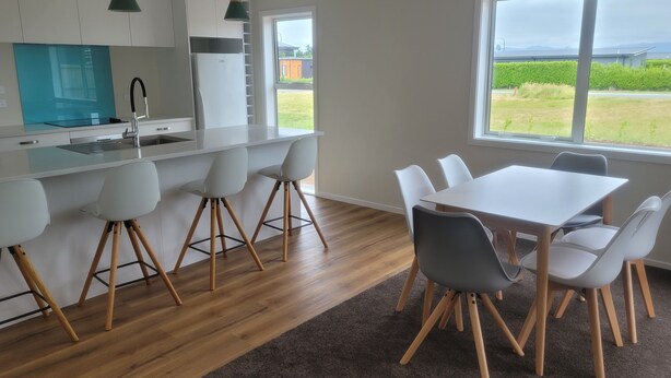 A modern kitchen with white cabinets, a stainless steel refrigerator, and a large window overlooking a grassy area.