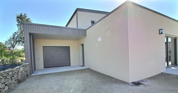 A modern two-story house with a garage, a stone wall, and a clear sky. - La Roz des plages - PLEUMEUR BODOU (PLEUMEUR BODOU)