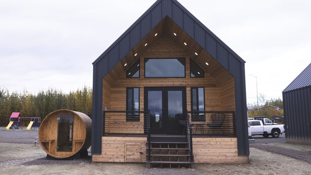 A modern wooden cabin with a steep gabled roof, large windows, and a wooden barrel-shaped structure nearby. - Lakefront Cottage with Sauna- #2 Coho (Wasilla)