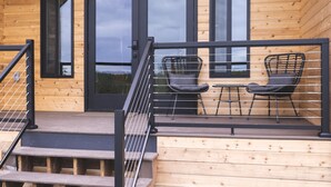 A wooden cabin with a deck, two chairs, and a staircase. - Lakefront Cottage with Sauna- #2 Coho (Wasilla)