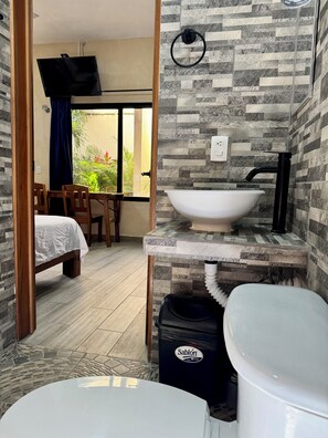 Une salle de bain avec un lavabo blanc, un robinet noir et une poubelle portant l’inscription « Sablón ».