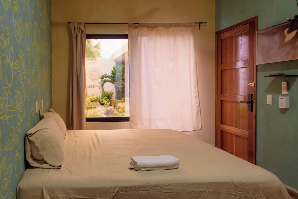 A bedroom with a bed, curtains, a window, and a wooden door.