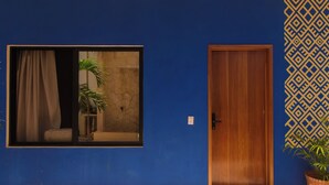A blue wall with a large window, a wooden door, and a patterned wall design. - Ceremonial Tulum (Tulum)