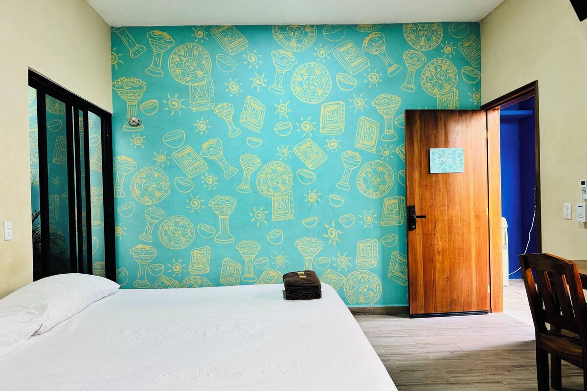 A room with a bed, a wooden door, and a blue wall with doodle patterns.