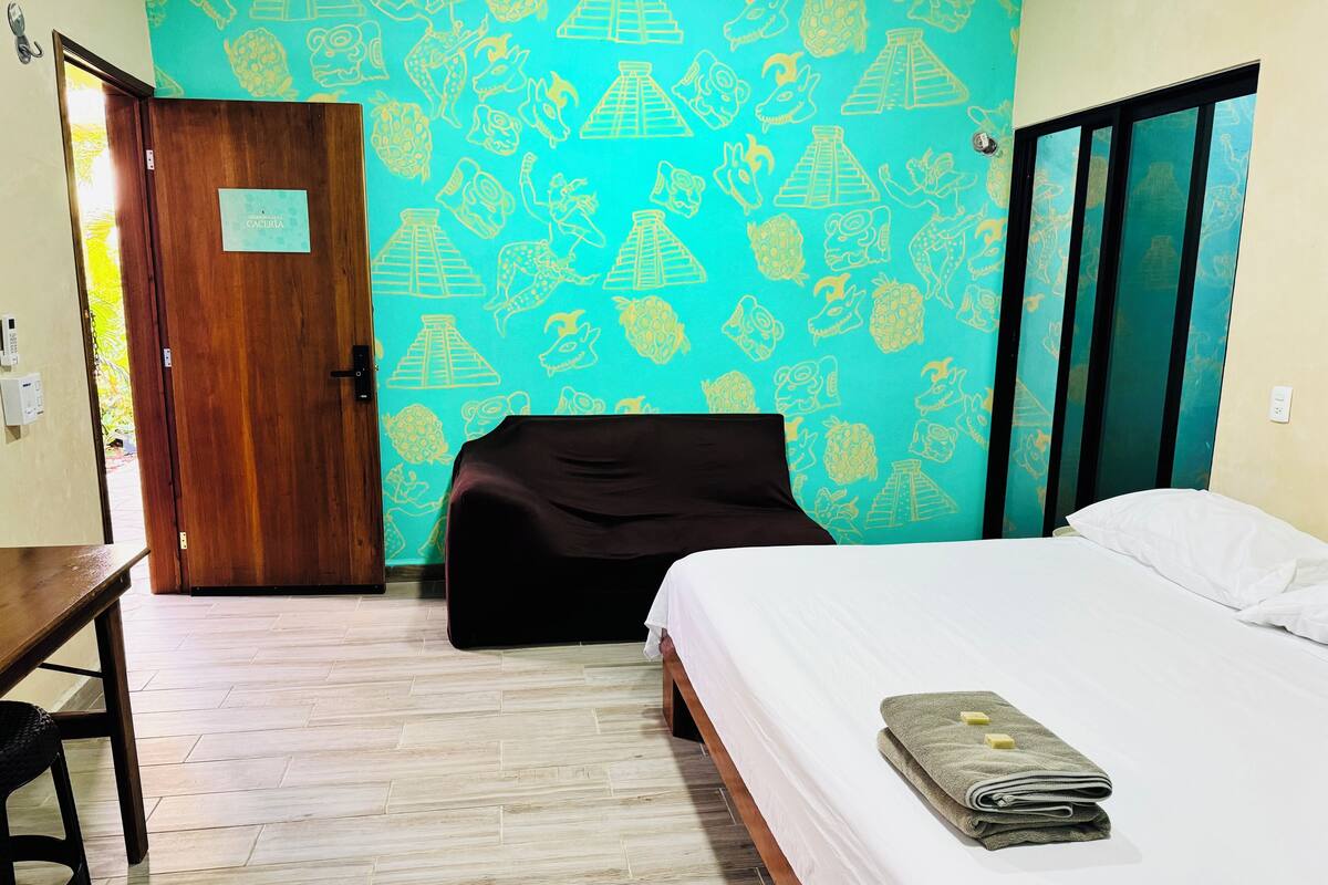 A hotel room with a bed, a desk, and a chair.