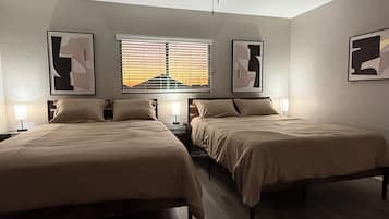 A bedroom with two beds, a window with blinds, and ceiling fans.