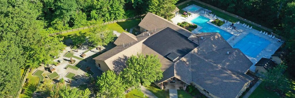 Ein Luftbild eines Wohnhauses mit Swimmingpool, überdachter Terrasse und gepflegtem Rasen.