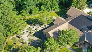 Luchtbeeld van een woonhuis met zwembad, overdekt terras en een verzorgd gazon.