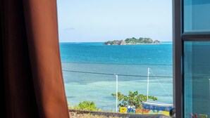 A view of a coastal area with clear blue water, a small island, and a boat in the distance. - Posada Three Cay Suites (Providencia)
