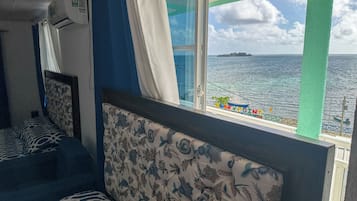 A room with a bed, a window with a view of the sea, and a sign reading "ROCKPOINT".