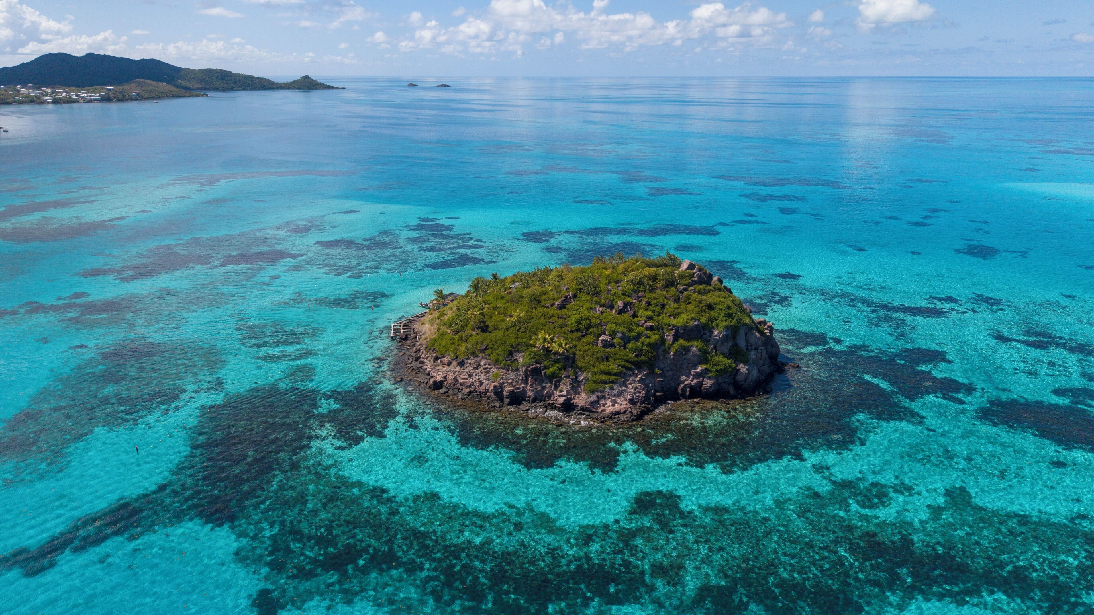 An aerial view of a small island with clear turquoise waters and a rocky terrain.