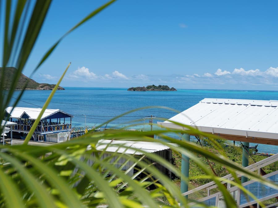 A coastal view with a small island, a white-roofed building, and a structure with a blue roof.
