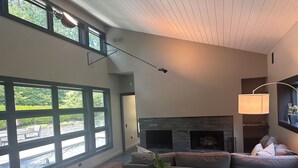 A spacious living room with a fireplace, large windows, and a dining area.