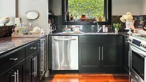 A modern kitchen with dark cabinets, a stainless steel sink, and a window above the counter.