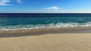 A beach with a clear view of the ocean and a sandy shore.