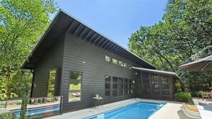 A modern house with a pool, large windows, and a patio area.