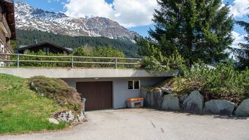 A mountain cabin with a wooden deck overlooking a snowy mountain range.