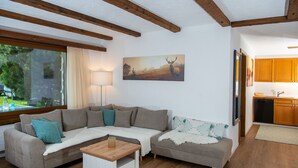 A cozy living room with a sectional sofa, a small coffee table, and a painting of a deer on the wall.
