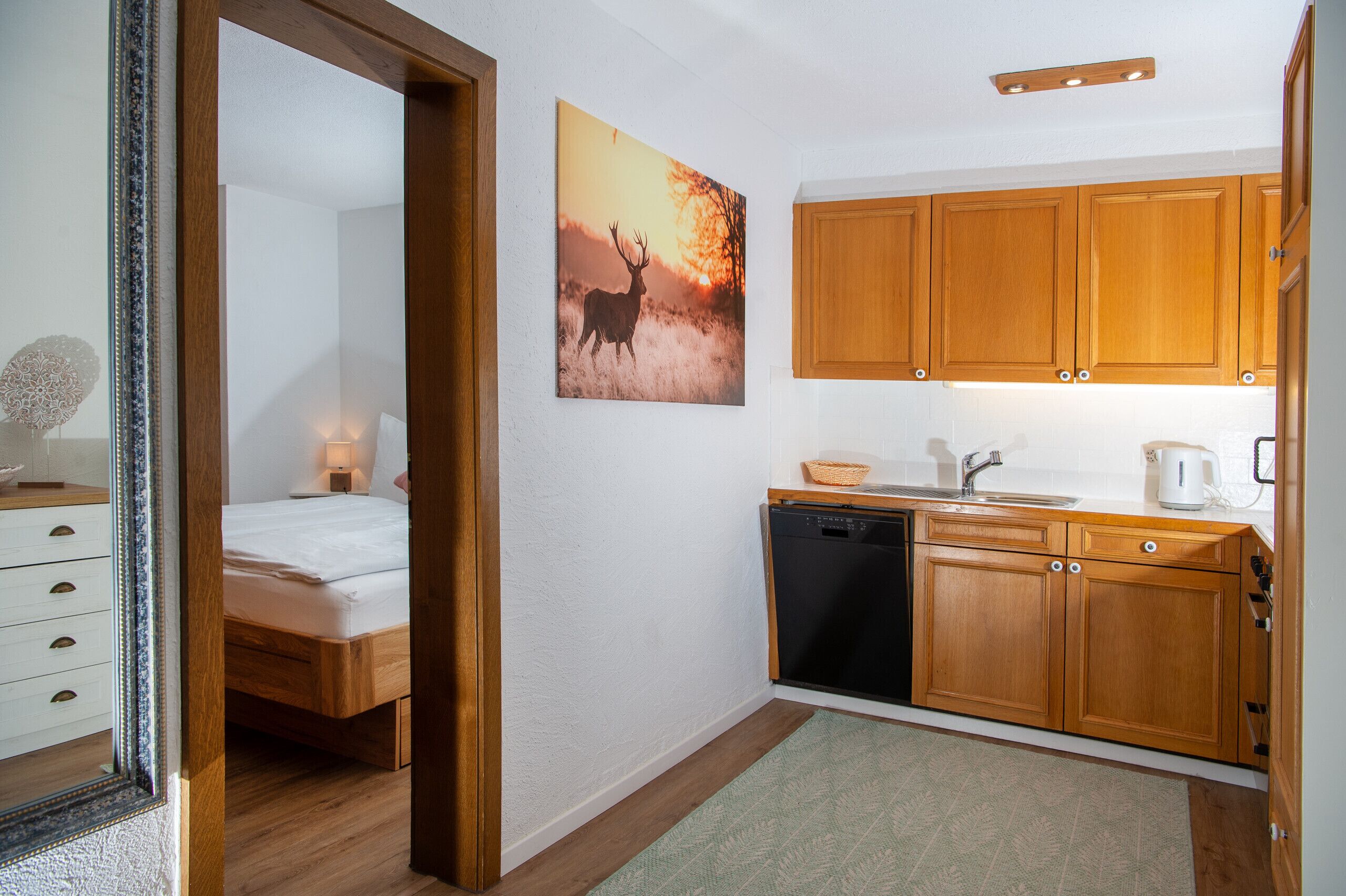 Une pièce comprenant un lit, une armoire en bois, un lavabo et un tableau représentant un cerf.
