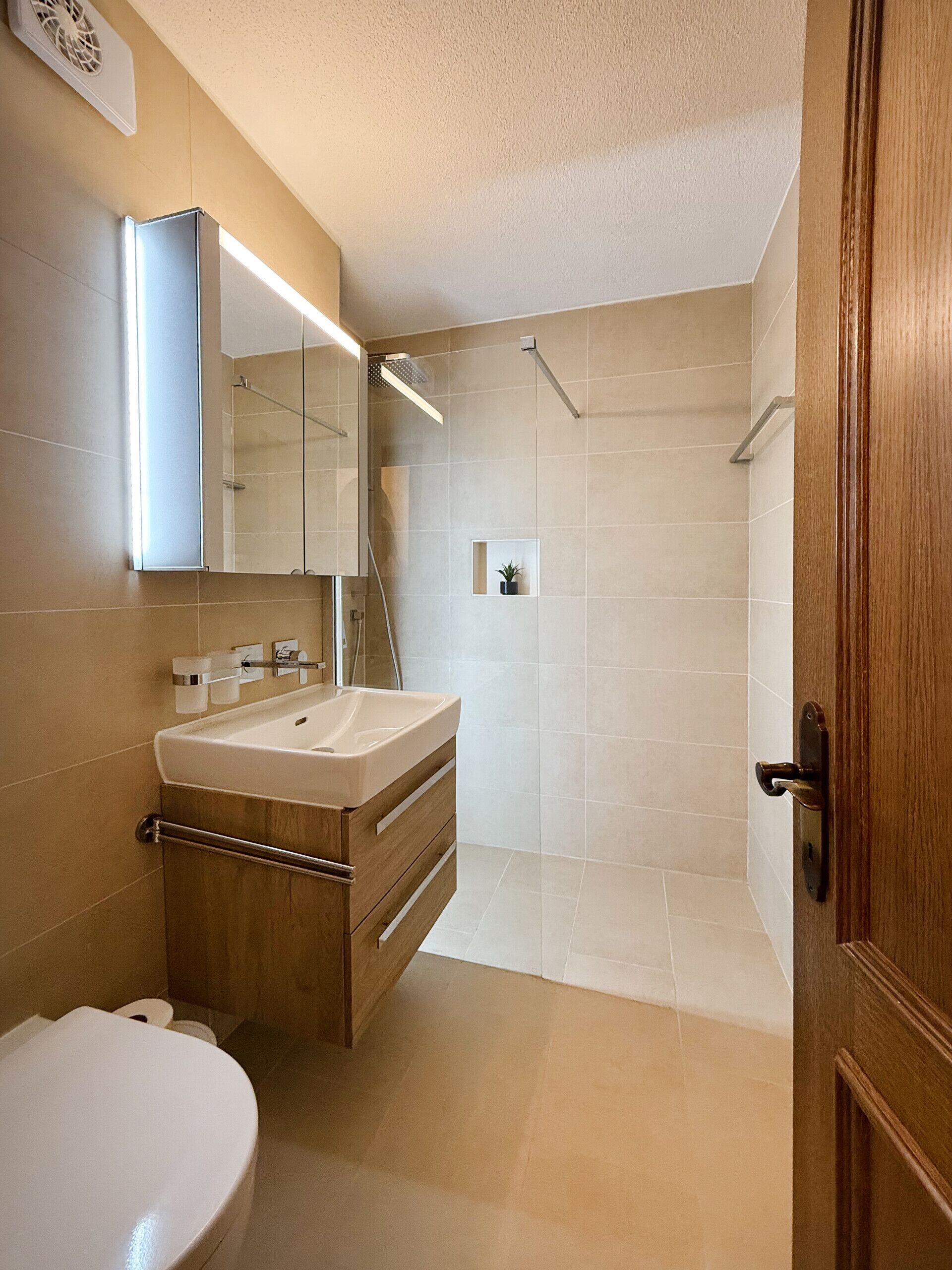 Een moderne badkamer met een wastafel, spiegel en douche.