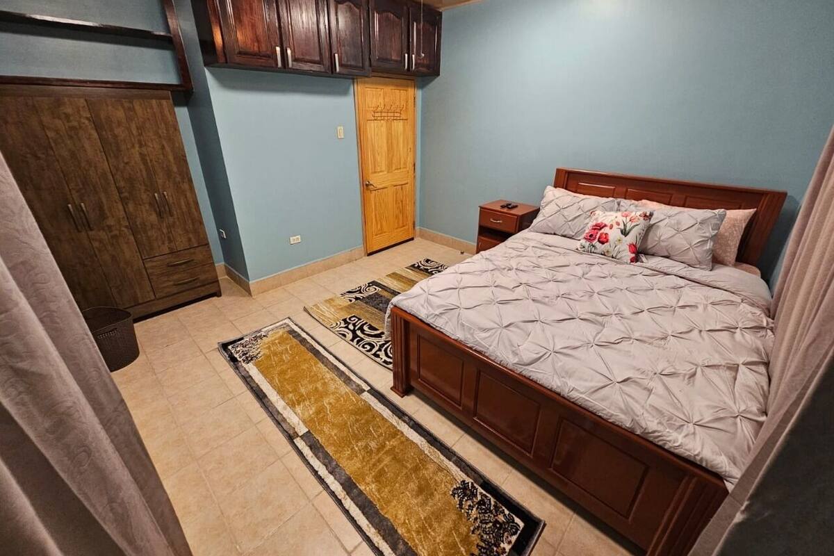 Une chambre à coucher avec un lit, une armoire en bois et un ventilateur de plafond.