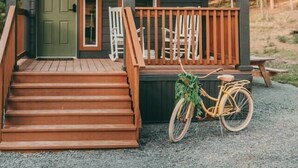 Una cabaña con un porche, escalones de madera y una bicicleta.