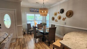 A dining area with wicker chairs, a glass table, and a chandelier.