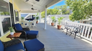 A covered porch with wicker furniture, potted plants, and a view of the neighborhood.