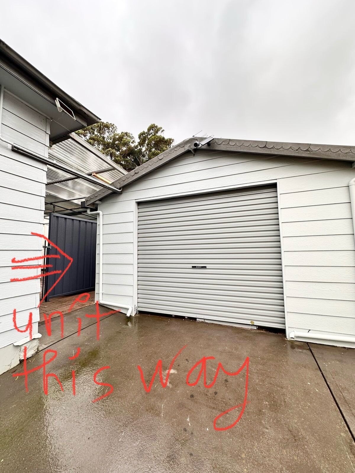 A garage with a closed roller door, adjacent to a building with white siding.