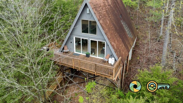 A cabin with a wooden deck, large windows, and a metal roof, surrounded by dense forest. - Steps from Bryce Resort - Ski slope views & golf (Basye)