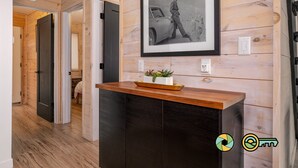 A hallway with wooden walls, a framed photograph on the wall, a wooden counter with a plant, and a door leading to another room. - Steps from Bryce Resort - Ski slope views & golf (Basye)