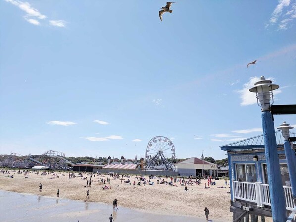 A beach with a Ferris wheel, a boardwalk, and a lighthouse.