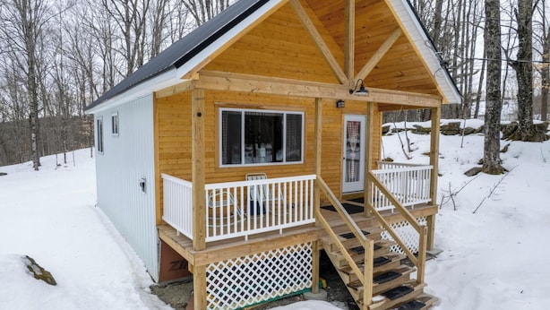 A wooden cabin with a porch, a window, and a door.