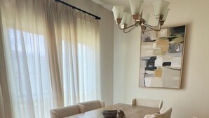 Un comedor con una mesa de madera y seis sillas, una araña y un cuadro en la pared.