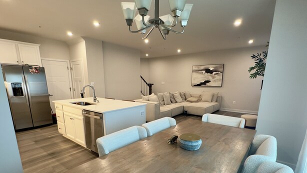 Una cocina moderna con una isla central, electrodomésticos de acero inoxidable y un comedor con mesa de madera y sillas acolchadas.