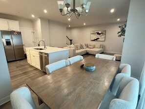 Una cocina moderna con una isla central, electrodomésticos de acero inoxidable y un comedor con mesa de madera y sillas acolchadas.