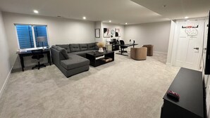 Una sala moderna con un sofá modular, un escritorio y un aro de baloncesto.