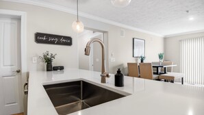 Een moderne keuken met een roestvrijstalen spoelbak, een hanglamp en een bord aan de muur.
