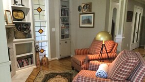 A cozy living room with a checkered sofa, a matching armchair, a floor lamp, and a bookshelf filled with books. - Charming 3-bedroom house in lovely Rome with WiFi, AC (Rome)