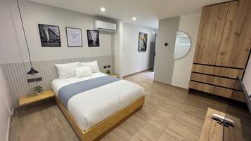 A modern bedroom with a wooden bed, a nightstand, a wall-mounted air conditioner, and a wardrobe with a mirror.