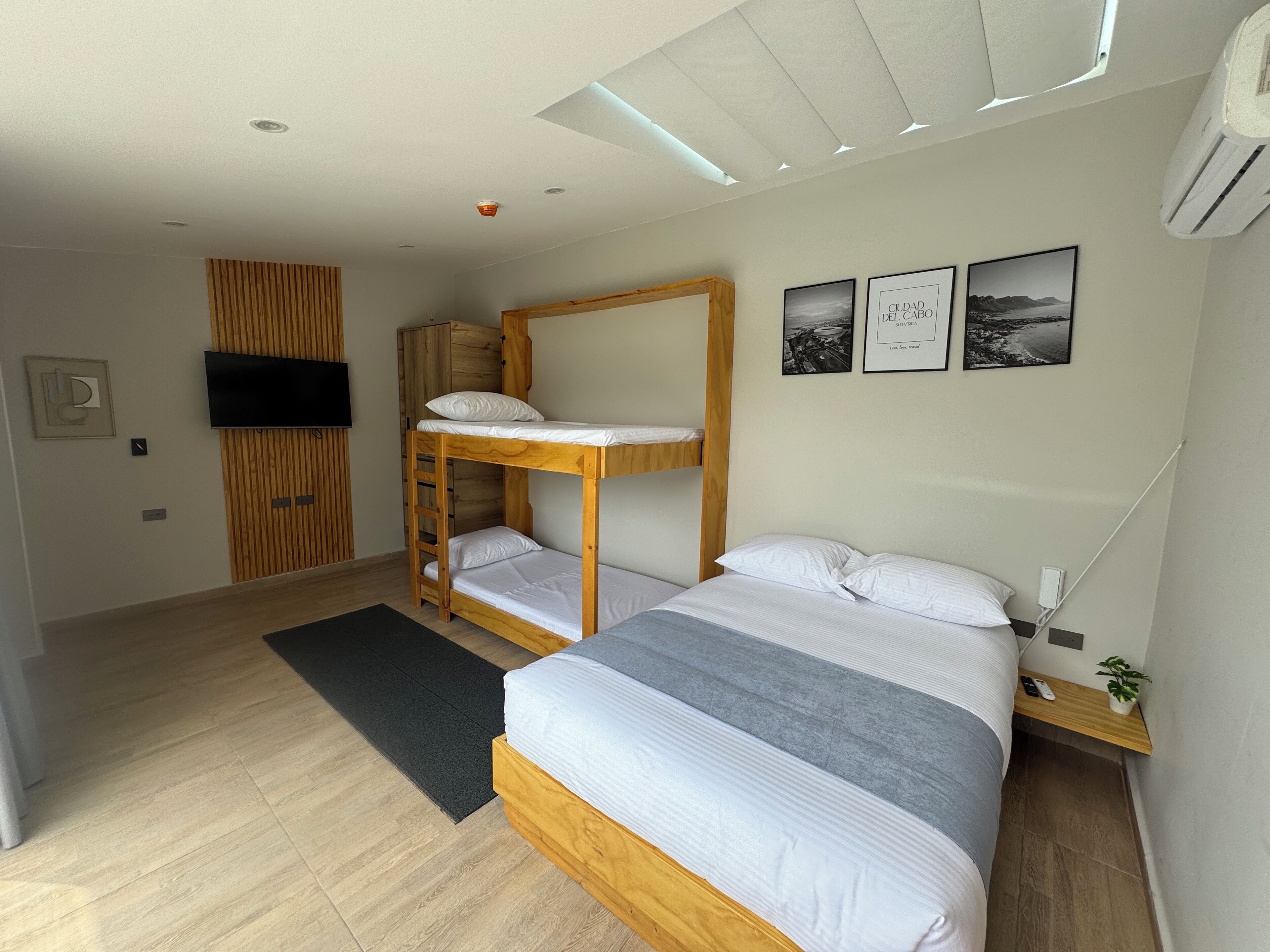 Une chambre moderne avec un lit superposé, un téléviseur à écran plat et trois tableaux encadrés accrochés au mur.