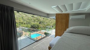 A modern hotel room with a large bed, a view of a swimming pool, and a balcony with glass railings. - Hotel San Gil House (San Gil)