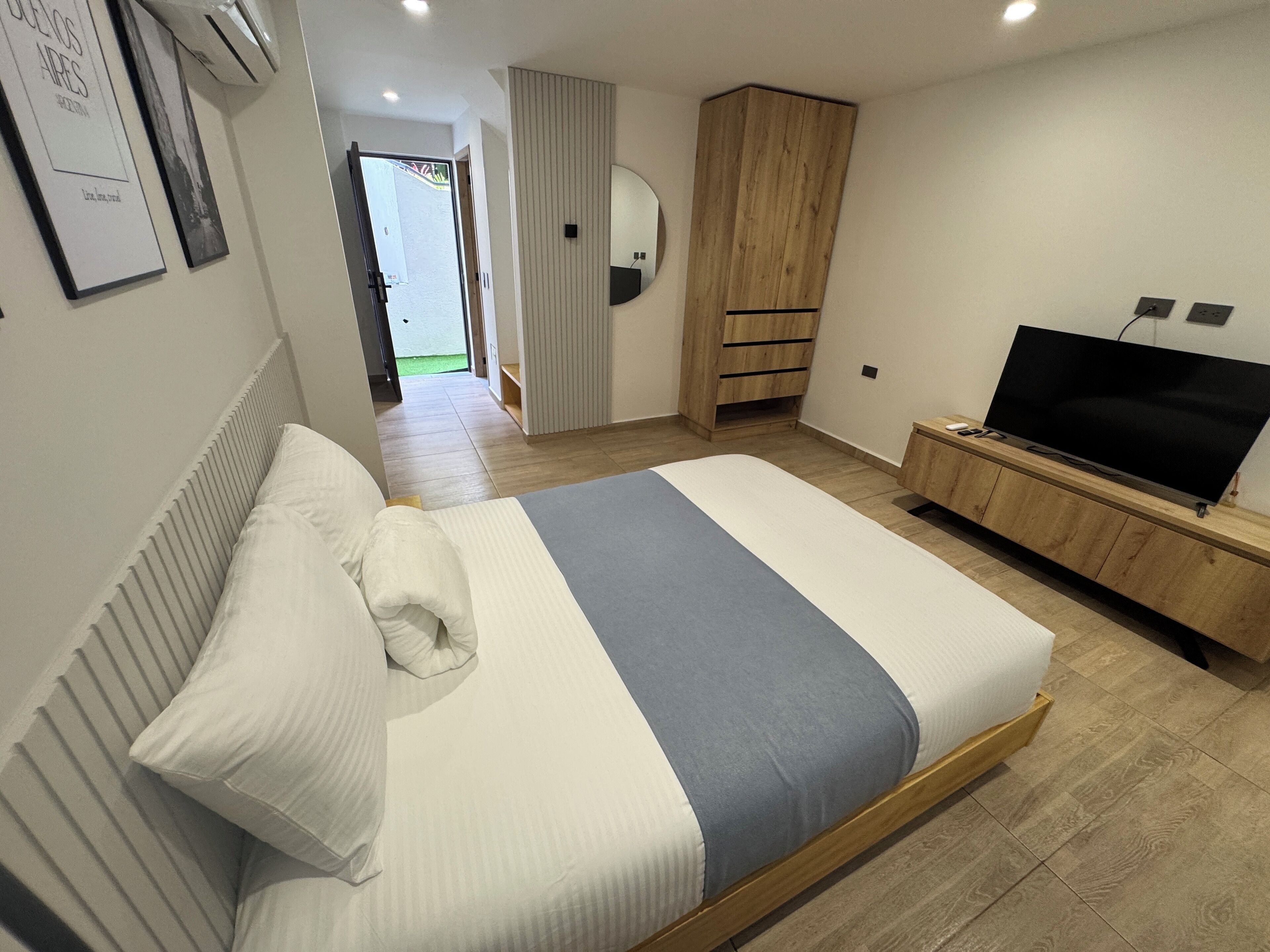 A modern bedroom with a bed, a TV, and a wardrobe.