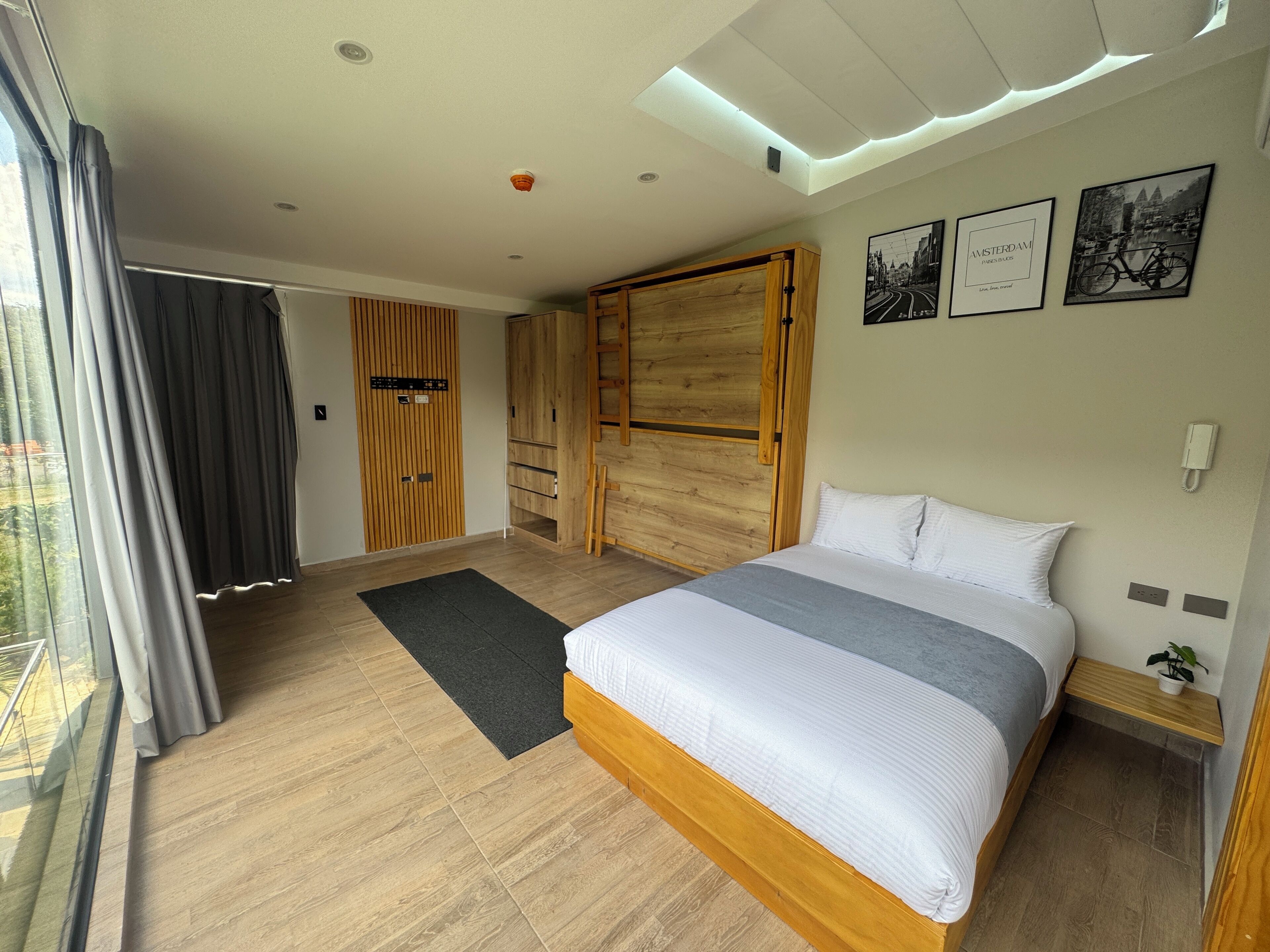 A modern bedroom with a large bed, wooden wardrobe, and a view of the outdoors.