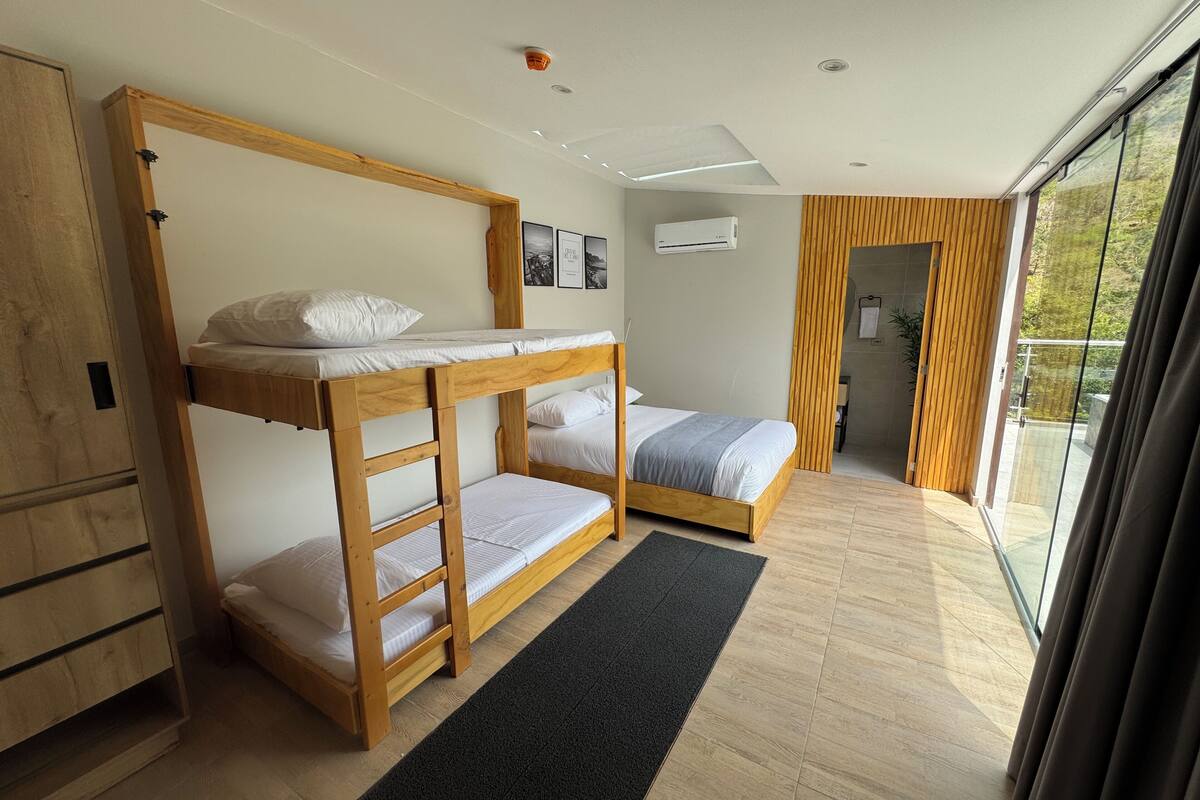 A modern bedroom with bunk beds, a large window, and a wooden wardrobe.